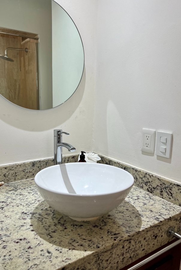 a bathroom sink with a round mirror above it