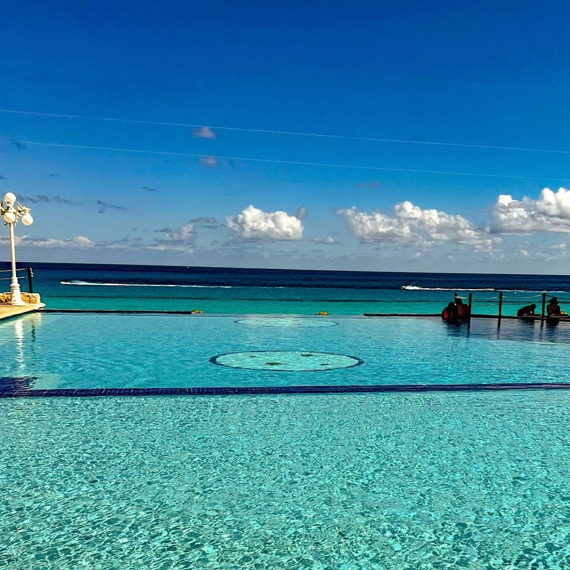 a large swimming pool with the ocean in the background