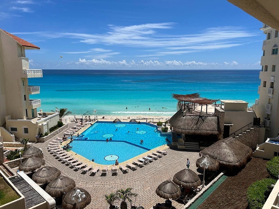 a large swimming pool surrounded by chairs and umbrellas overlooking the ocean
