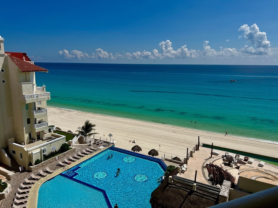 a large swimming pool surrounded by chairs and a beach