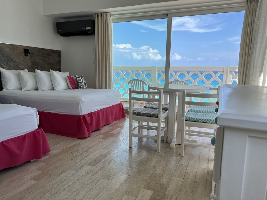 a hotel room with two beds and a table with a view of the ocean