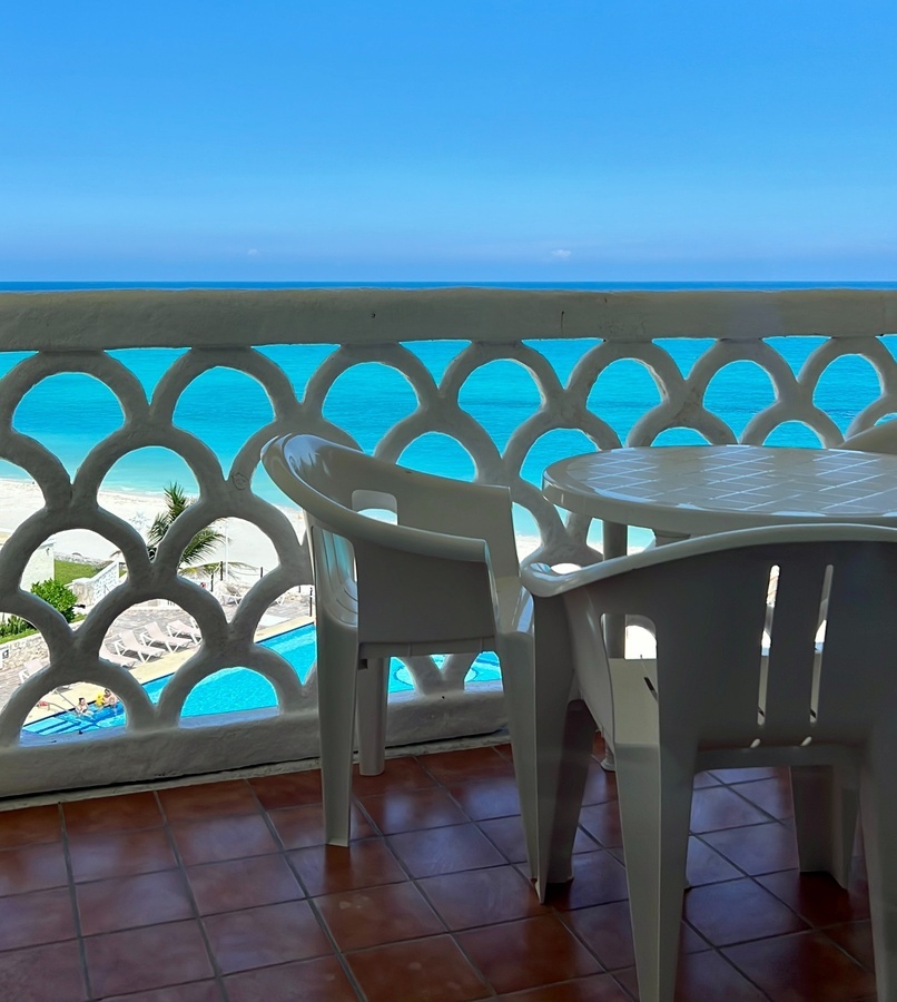 a table and chairs on a balcony overlooking the ocean