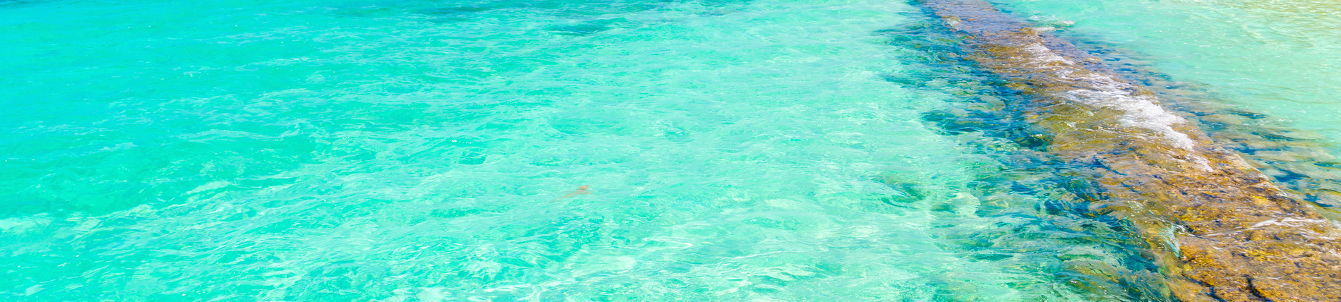 a turquoise water surface with a rock in the middle