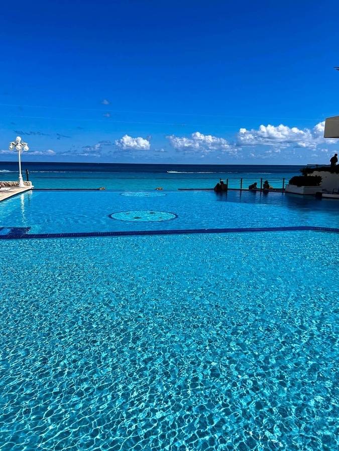 a large swimming pool with the ocean in the background