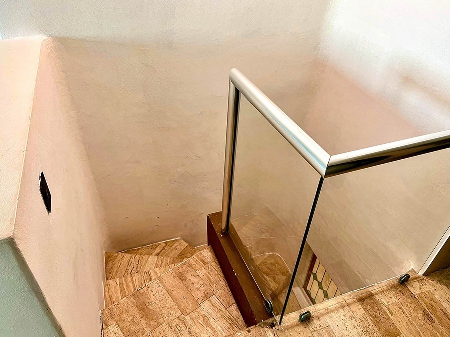 a staircase with a glass railing going up to the second floor