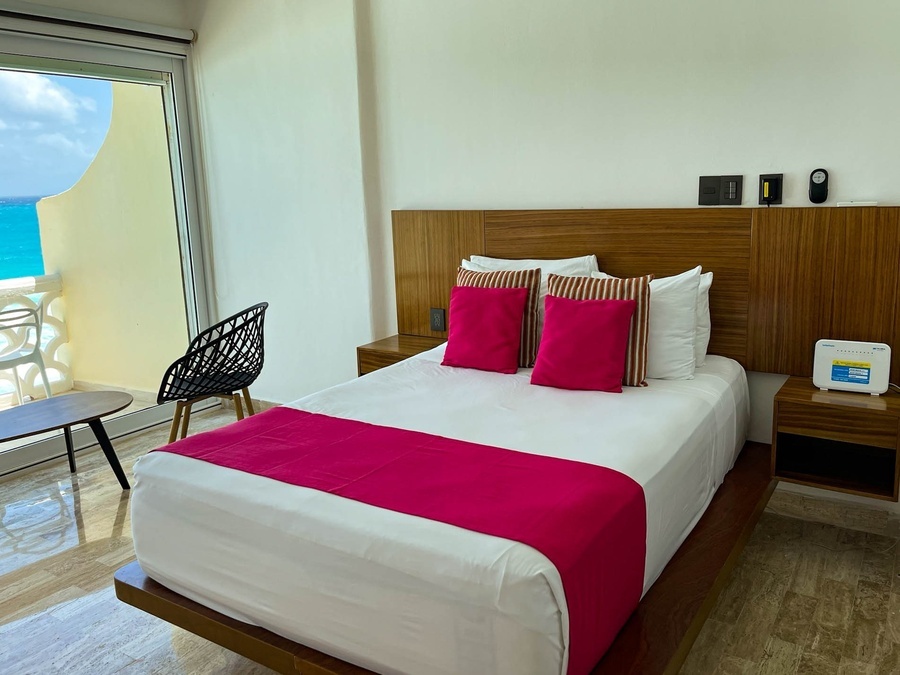 a hotel room with a bed with pink pillows