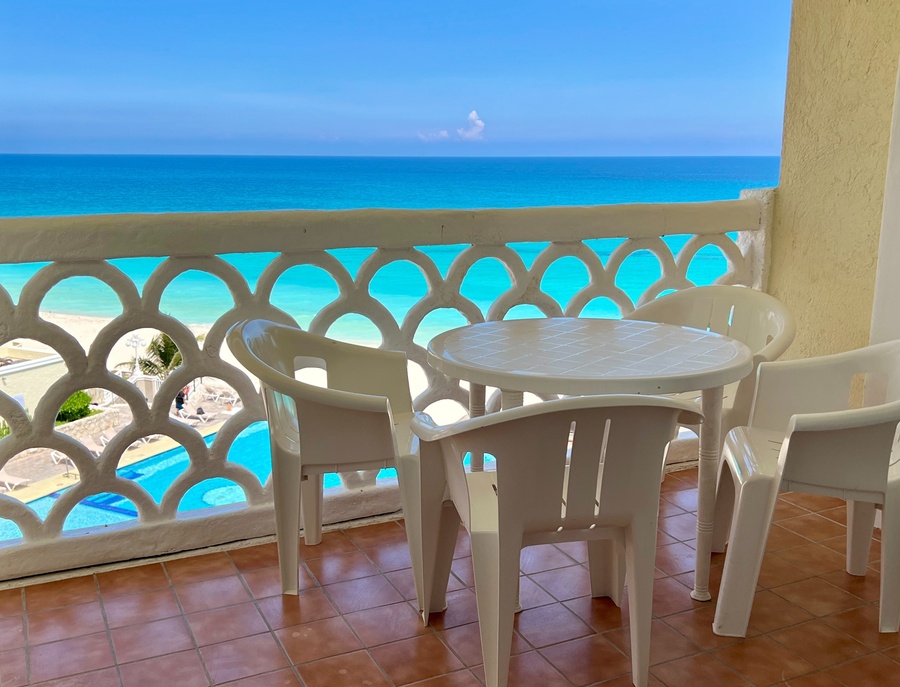una mesa y sillas en un balcón con vista al océano