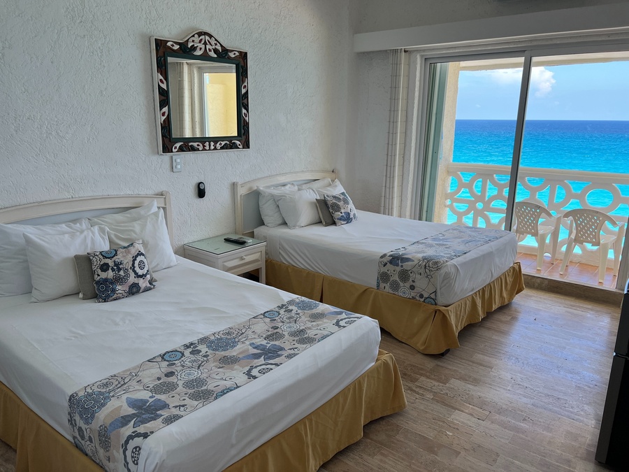 a hotel room with two beds and a balcony overlooking the ocean
