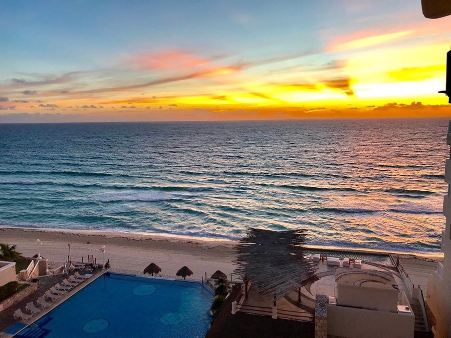 a sunset over the ocean with a swimming pool in the foreground