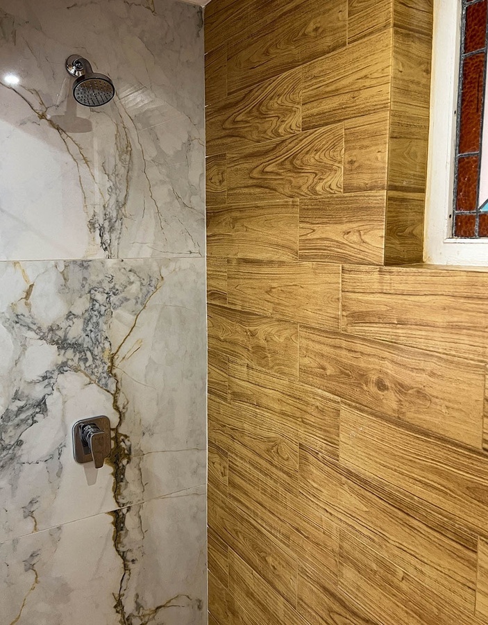 a shower with marble and wood tiles and a stained glass window