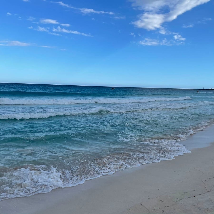 waves crashing on a sandy beach with a blue sky in the background