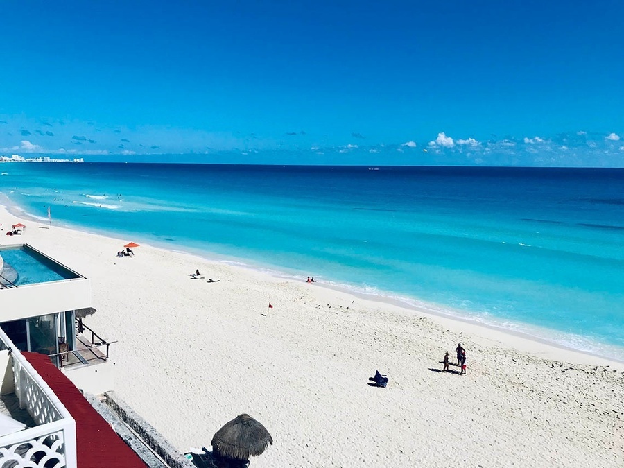 a view of a beach with a pool in the background