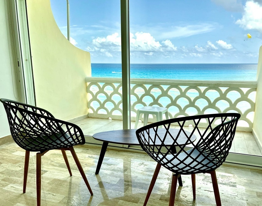 two chairs and a table on a balcony overlooking the ocean