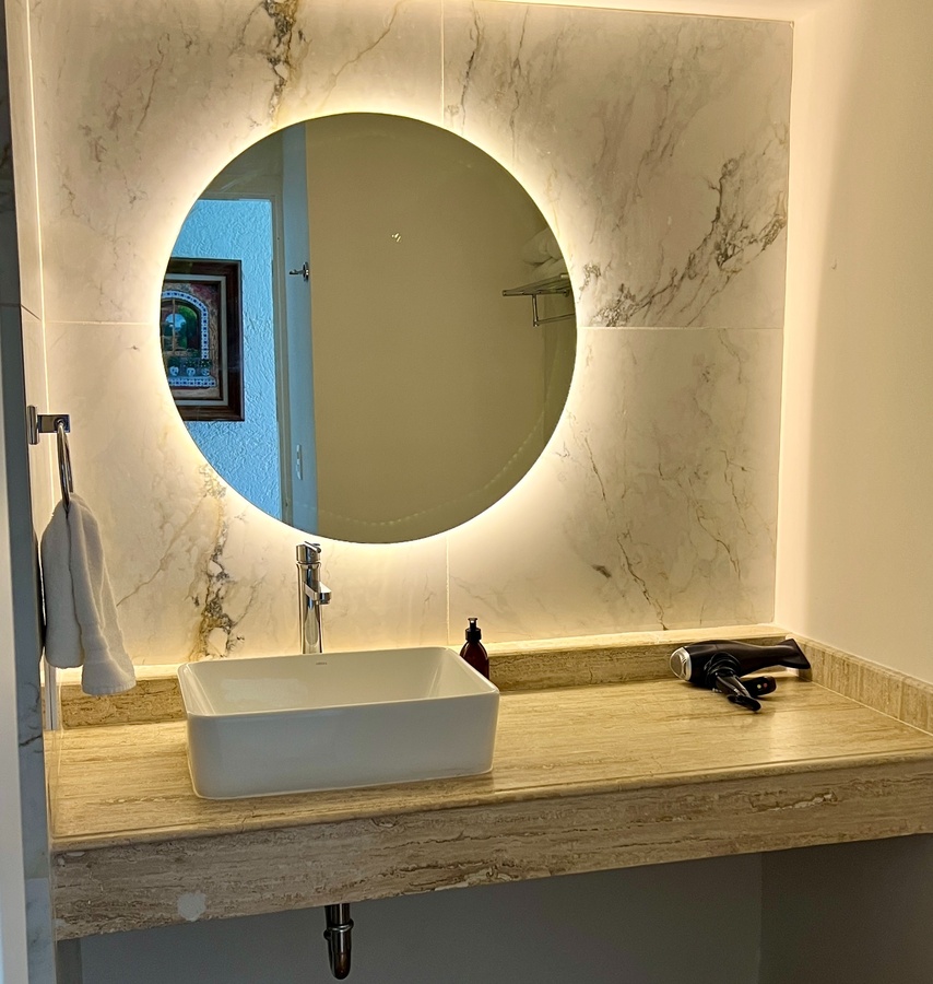 a bathroom with a sink and a round mirror