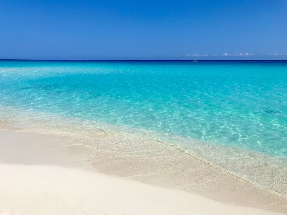 a white sandy beach with a boat in the distance