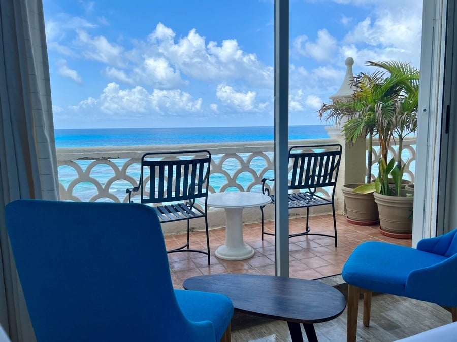 two chairs and a table on a balcony overlooking the ocean