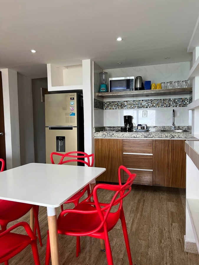 a kitchen with a white table and red chairs