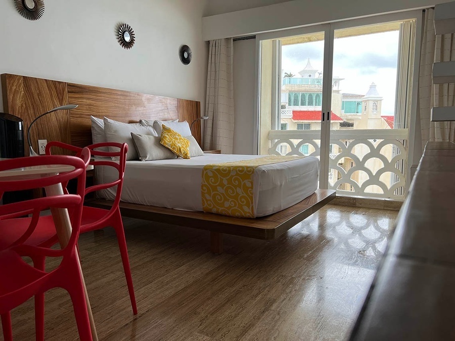 a hotel room with a king size bed and red chairs