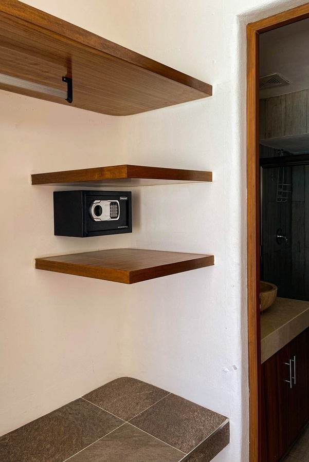 a safe is mounted on a wooden shelf in a bathroom