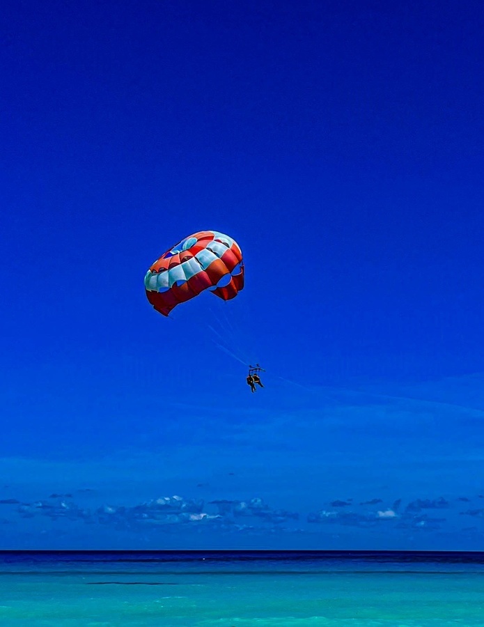 a colorful parachute is flying over the ocean