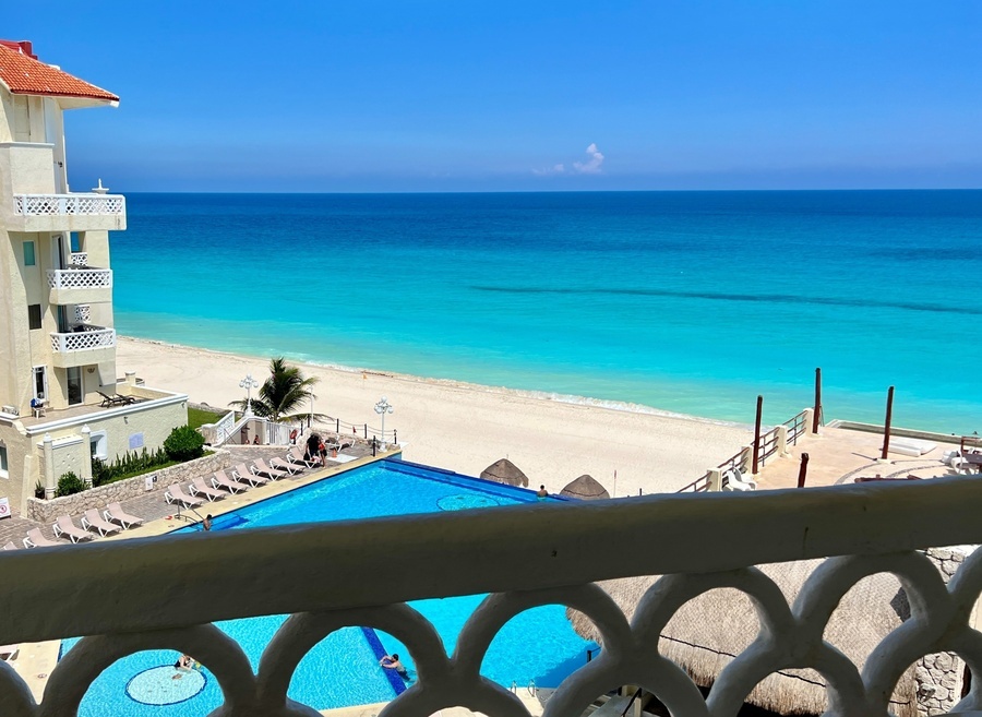 a view of a swimming pool and beach from a balcony