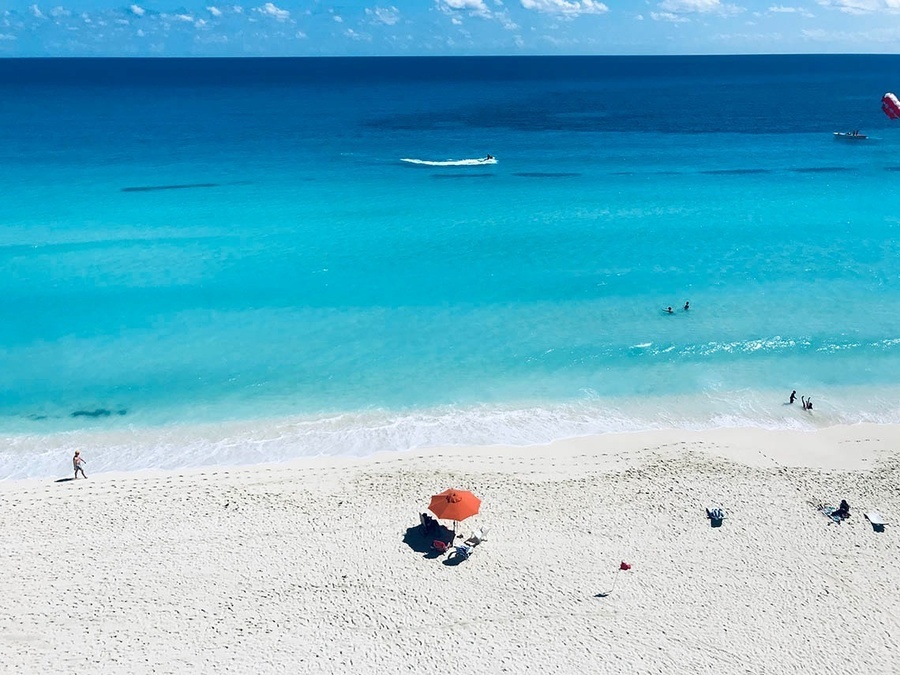 a beach with a red umbrella in the sand