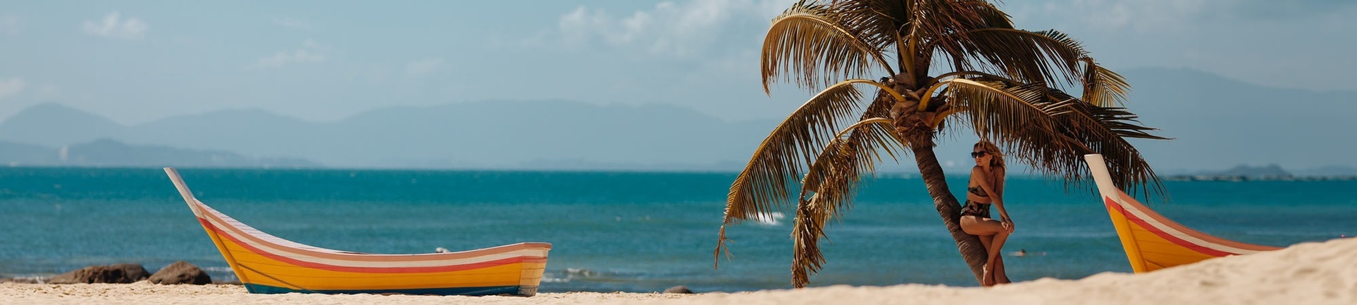 una mujer se sienta en una palmera en la playa