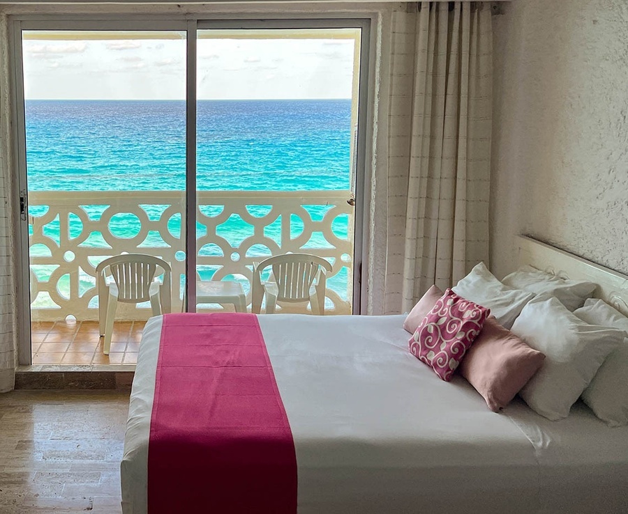 a hotel room with a bed and a balcony overlooking the ocean