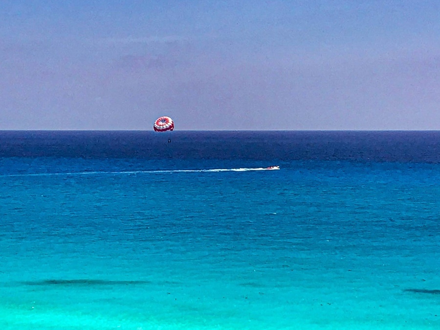 a red and white parachute is flying over the ocean
