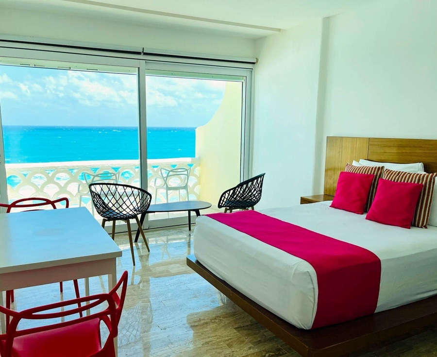 a hotel room with a bed and chairs with a view of the ocean