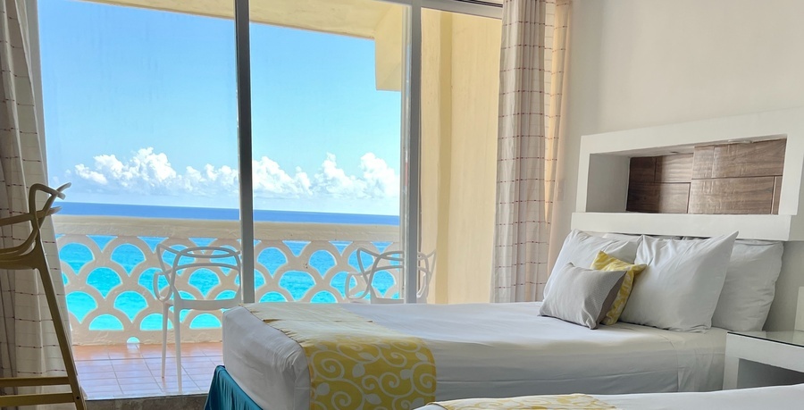 a hotel room with two beds and a balcony overlooking the ocean