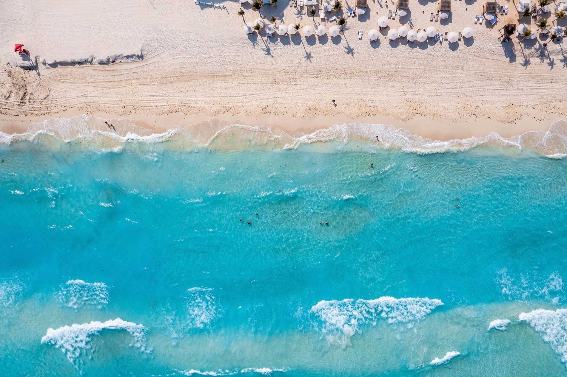 an aerial view of a beach with umbrellas and chairs