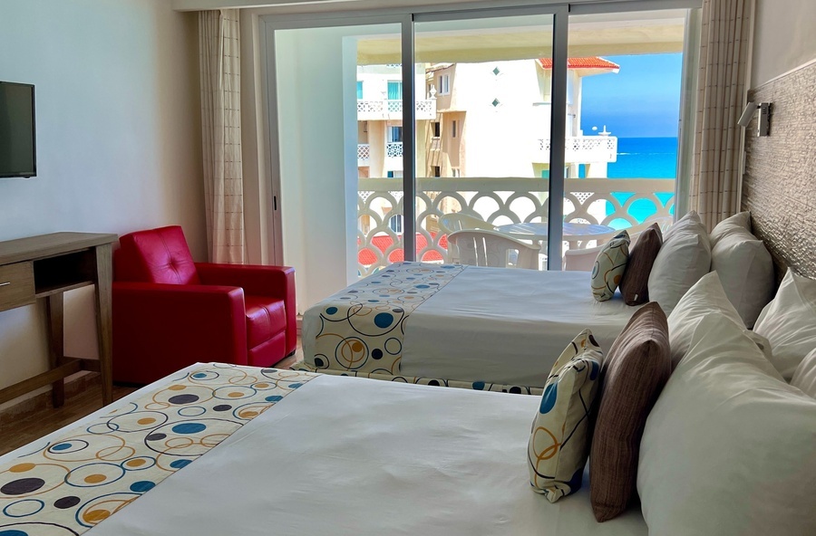 a hotel room with two beds and a red chair