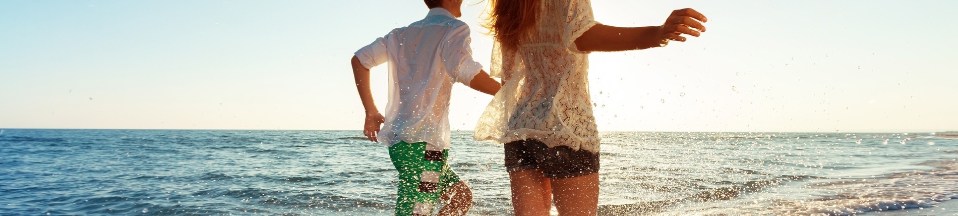 a man and a woman are walking into the ocean holding hands