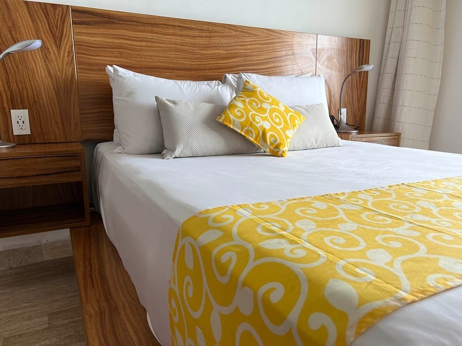 a bed with white sheets and a yellow blanket