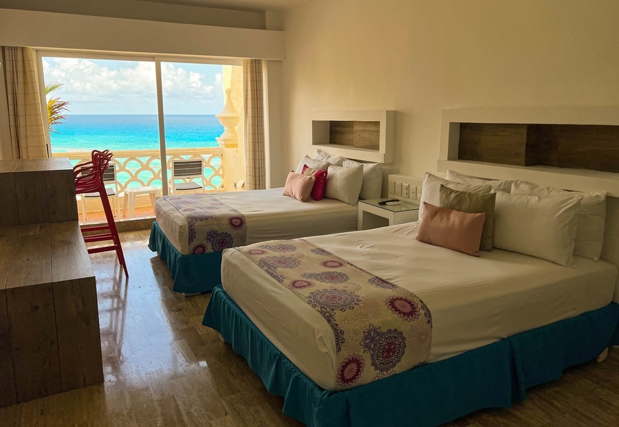 a hotel room with two beds and a balcony overlooking the ocean