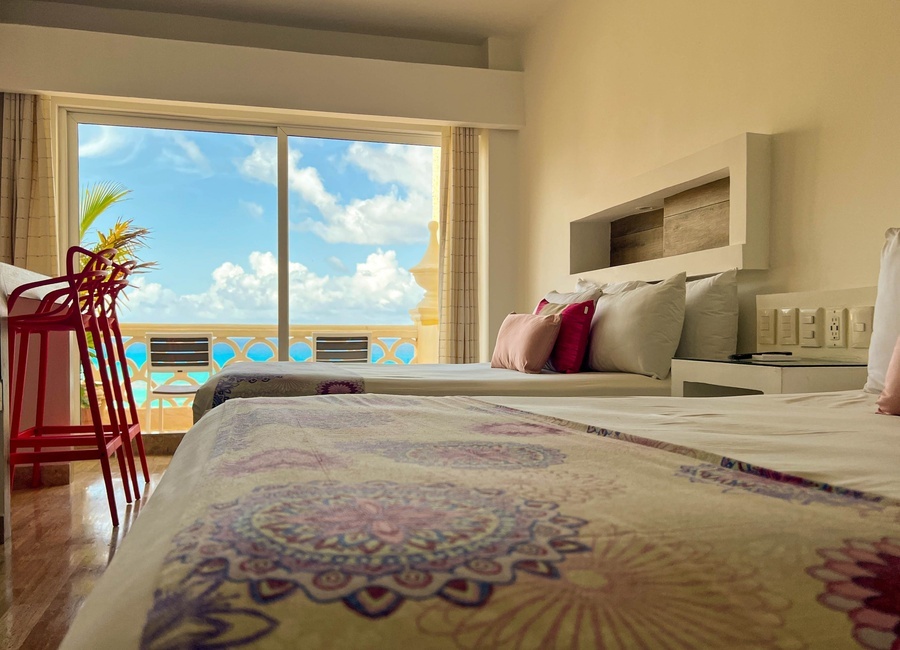 a hotel room with two beds and a balcony overlooking the ocean