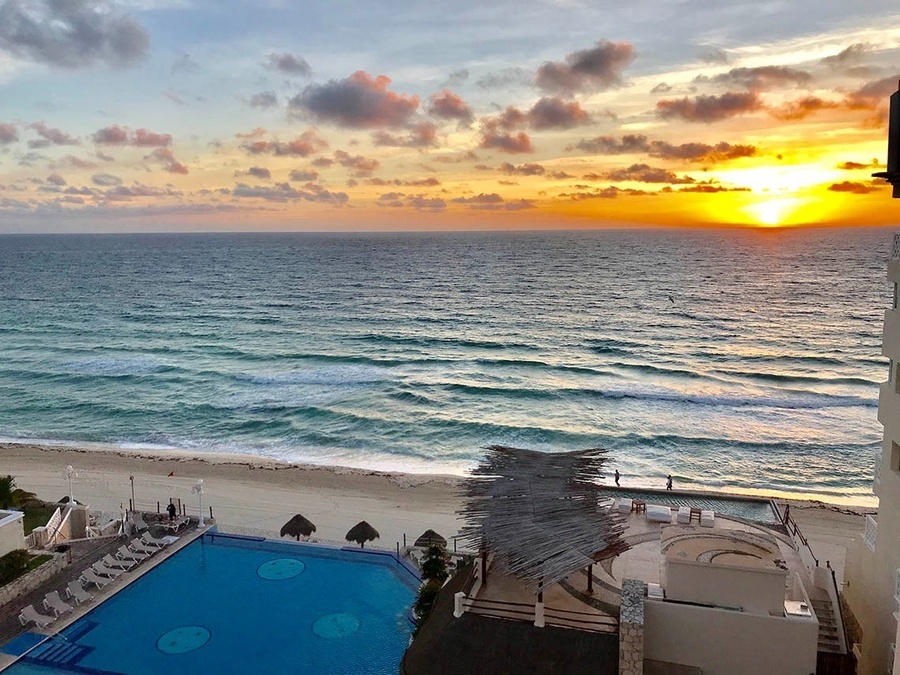 a sunset over the ocean with a swimming pool in the foreground