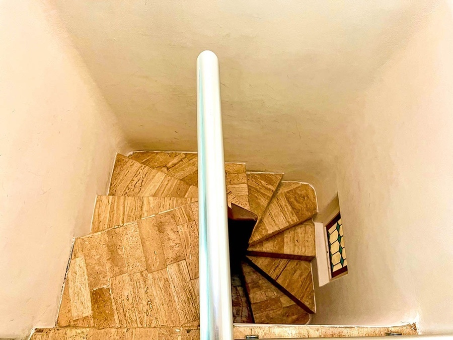 a spiral staircase with a white railing and a stained glass window