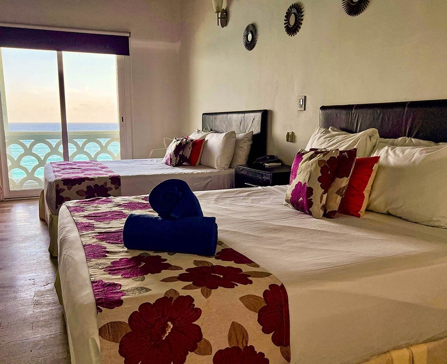 a hotel room with two beds and a view of the ocean