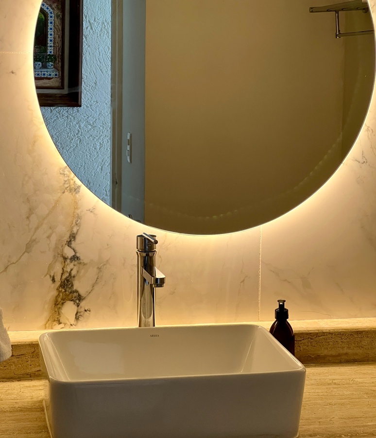 a bathroom sink with a round mirror above it