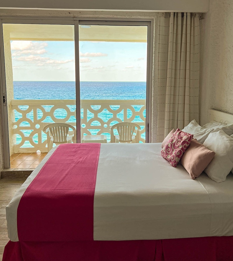 a hotel room with a bed and a balcony overlooking the ocean