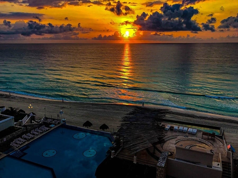 a sunset over the ocean with a swimming pool in the foreground