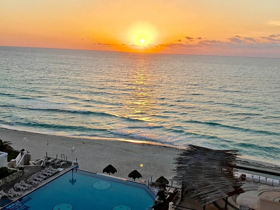 a sunset over the ocean with a swimming pool in the foreground