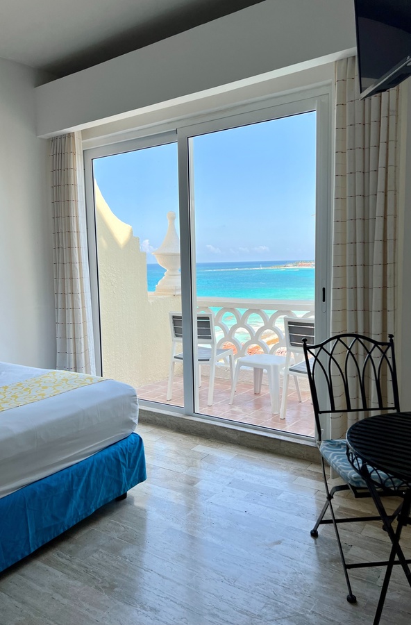 una habitación con una cama y una mesa con una vista al océano