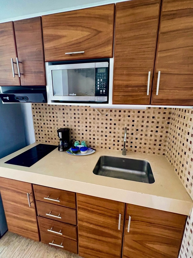 a mabe microwave sits above a sink in a kitchen