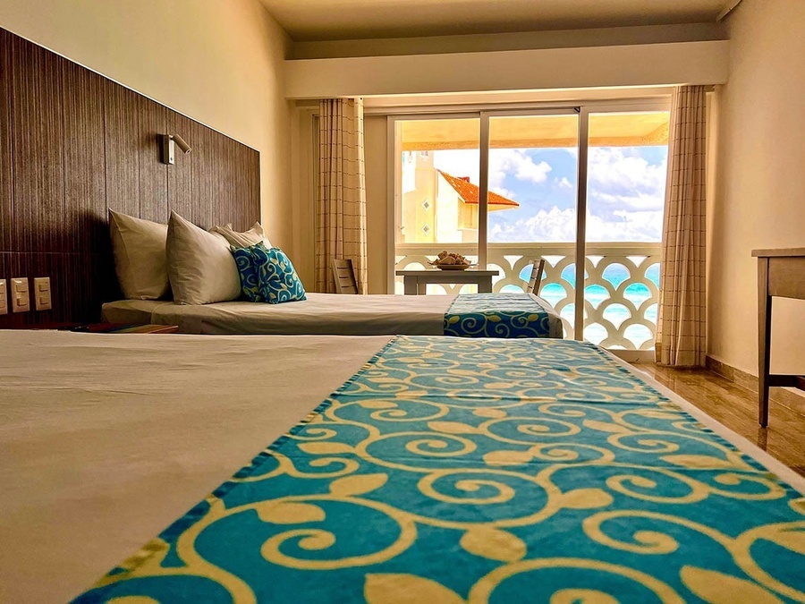 a hotel room with two beds and a balcony overlooking the ocean