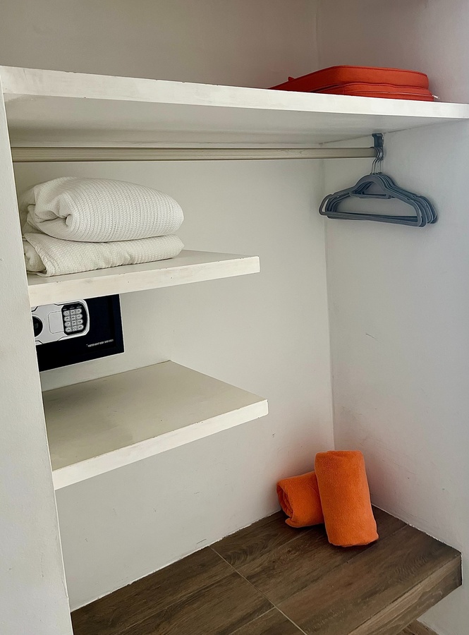 a safe in a closet with clothes on the shelves