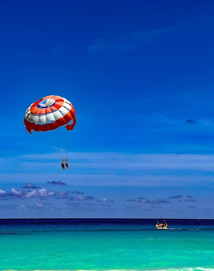 two people are parasailing over the ocean with a boat in the background