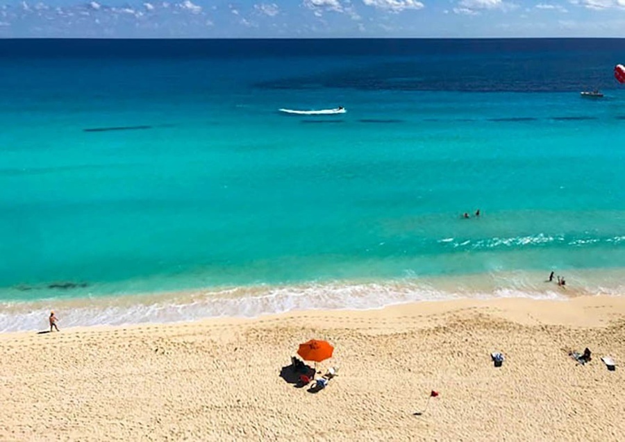 an orange umbrella sits on a sandy beach near the ocean
